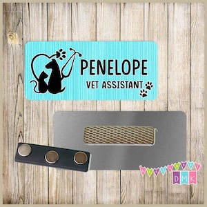 May include: A turquoise blue name tag with a black silhouette of a dog and cat with a stethoscope and the text "PENELOPE VET ASSISTANT" with black paw prints.