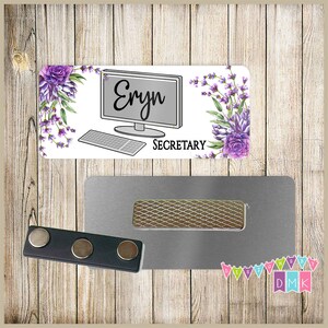 May include: A white name tag with a purple floral design and a computer icon. The name tag says "Eryn" and "Secretary".