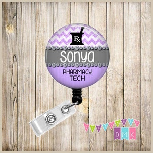 May include: Purple and white chevron patterned badge reel with a black pharmacy symbol and the text "Sonya Pharmacy Tech". The badge reel has a silver trim with rhinestones.