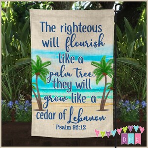 May include: A garden flag with a burlap texture featuring a beach scene with palm trees and ocean waves. The text reads "The righteous will flourish like a palm tree, they will grow like a cedar of Lebanon Psalm 92:12".