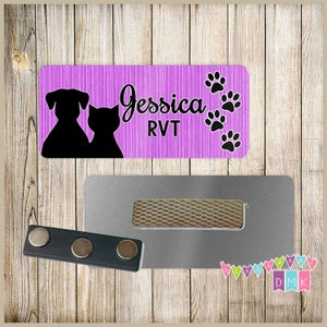 May include: Purple and black name tag with the text "Jessica RVT" and paw prints. The name tag is attached to a silver magnetic name tag holder.