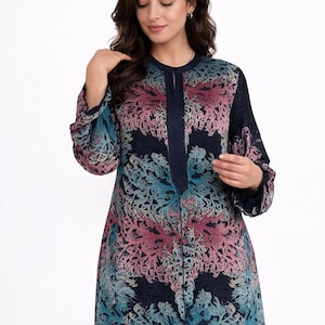 May include: A long-sleeved dress with a navy blue background and a floral pattern in teal and pink. The dress has a mandarin collar and a button-down front. The sleeves are long and loose, and the dress falls to the ankles.