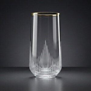 May include: A tall, clear glass with a gold rim. The glass features vertical etched lines at the bottom, creating a decorative pattern. The elegant design is suitable for serving beverages.