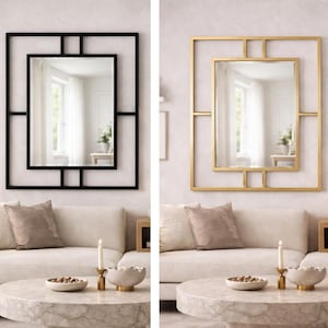Puede incluir: Dos espejos de pared decorativos. Uno tiene un marco geométrico negro, el otro un marco dorado. Ambos espejos tienen un espejo rectangular dentro de un marco cuadrado. Se exhiben sobre un sofá blanco en un salón.