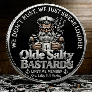 Peut inclure: Une pièce de monnaie argentée et noire avec le texte "WE DON'T RUST, WE JUST SWEAR LOUDER" sur le bord. La pièce représente un marin de dessin animé avec une longue barbe blanche, tenant une tasse avec une ancre. Le texte "Olde Salty BASTARDS" est en dessous.