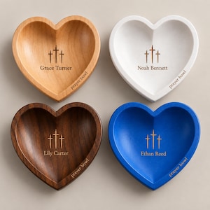 May include: Four heart-shaped bowls in light wood, white, dark wood, and blue. Each bowl features an engraving of three crosses, a name, and the text "prayer bowl". The names are Grace Turner, Noah Bennett, Lily Carter, and Ethan Reed.