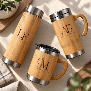 May include: A cylindrical bamboo and stainless steel water bottle engraved with the initials LF and the name Logan Ford, alongside two bamboo and stainless steel mugs with handles, one engraved with AB and Audrey Brooks, the other with CM and Claire Miller.