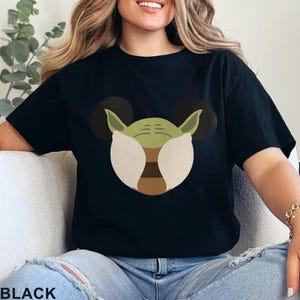 May include: Black t-shirt featuring a graphic of a green character with large ears, resembling a popular movie character. The character's face is designed with white, brown, and green elements. The word "BLACK" is printed at the bottom.