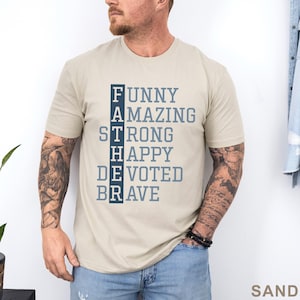 May include: Sand-colored t-shirt with the word "FATHER" spelled vertically, with each letter followed by a descriptive word: Funny, Amazing, Strong, Happy, Devoted, and Brave. The word "SAND" is printed in the bottom right corner.