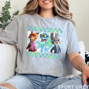 May include: Sport grey t-shirt featuring three cartoon characters: a fox in a pink shirt, a blue snake, and a rabbit in a blue jacket. The design is framed with a blue and green checkered pattern. The words "SPORT GREY" are printed at the bottom.