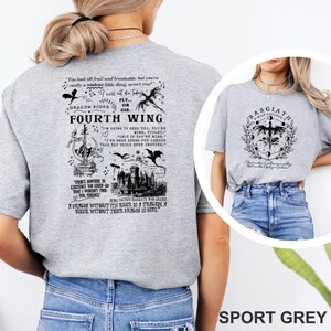 May include: Sport grey t-shirts with black graphic designs. One shirt features text and illustrations related to "Fourth Wing" and "Dragon Rider." The other shirt displays a circular design with the text "Basgiath War College."