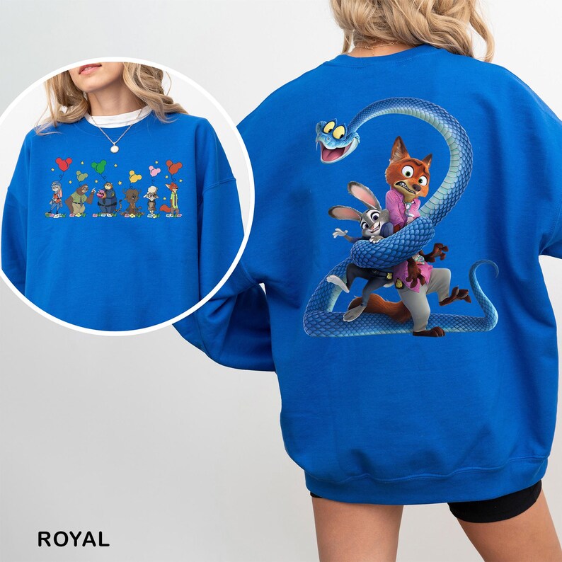May include: A royal blue crewneck sweatshirt featuring a large graphic on the back of a blue snake coiled around a rabbit and a fox character. A smaller circular inset shows the front of the sweatshirt with a line of cartoon characters holding balloons.