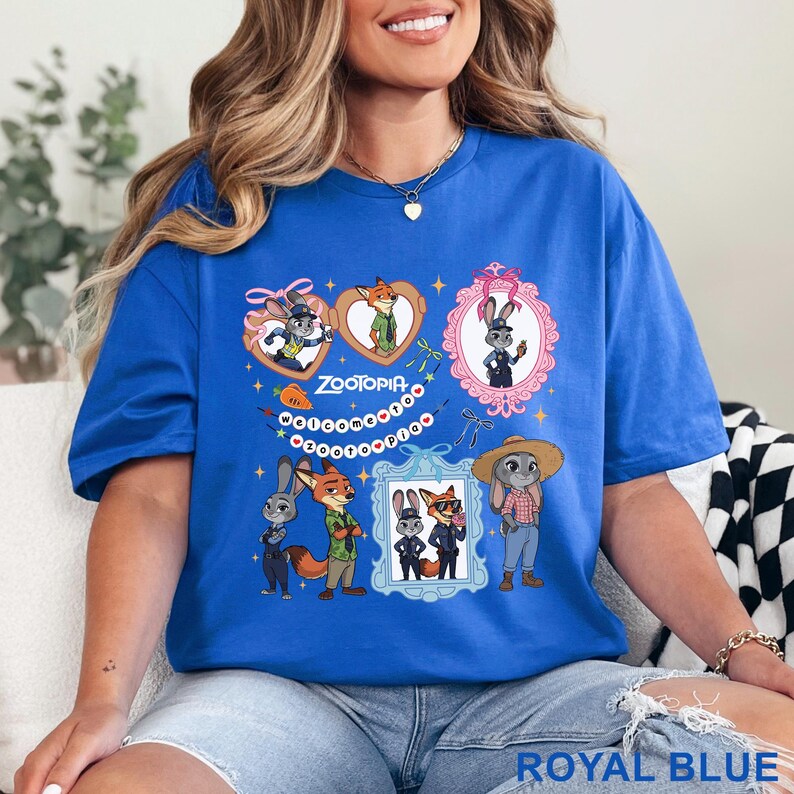 Puede incluir: Una camiseta azul real con un estampado gr&aacute;fico de los personajes de Zootopia, Judy Hopps y Nick Wilde. El dise&ntilde;o incluye varias ilustraciones de los personajes en marcos, una zanahoria y el texto "ZOOTOPIA WELCOME TO ZOOTOPIA".