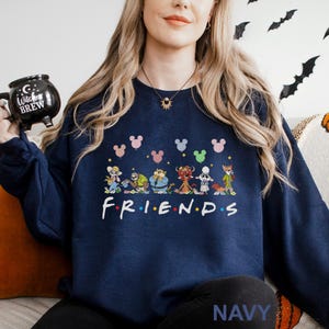 May include: Navy blue sweatshirt featuring a colorful graphic of cartoon characters and the word "FRIENDS" in white. Above the characters are Mickey Mouse head shapes in various colors. The word "NAVY" is printed at the bottom.