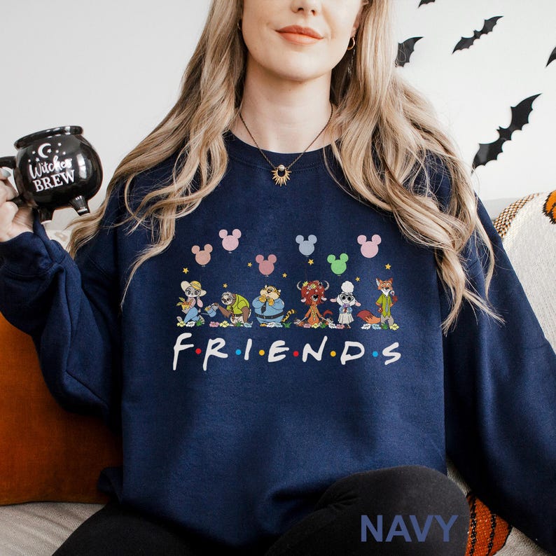 May include: Navy blue sweatshirt featuring a colorful graphic of cartoon characters and the word "FRIENDS" in white. Above the characters are Mickey Mouse head shapes in various colors. The word "NAVY" is printed at the bottom.