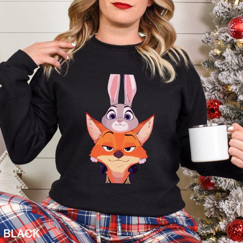 May include: Black sweatshirt featuring a cartoon image of Judy Hopps and Nick Wilde from Zootopia. The sweatshirt has a crew neck and long sleeves. The word "BLACK" is printed at the bottom.