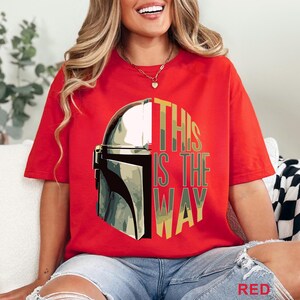Pu&ograve; includere: Una t-shirt rossa a maniche corte con una grafica di un casco mandaloriano argentato sul lato sinistro e il testo THIS IS THE WAY in un motivo mimetico sul lato destro. La maglietta presenta un girocollo e un design dalla vestibilit&agrave; ampia.
