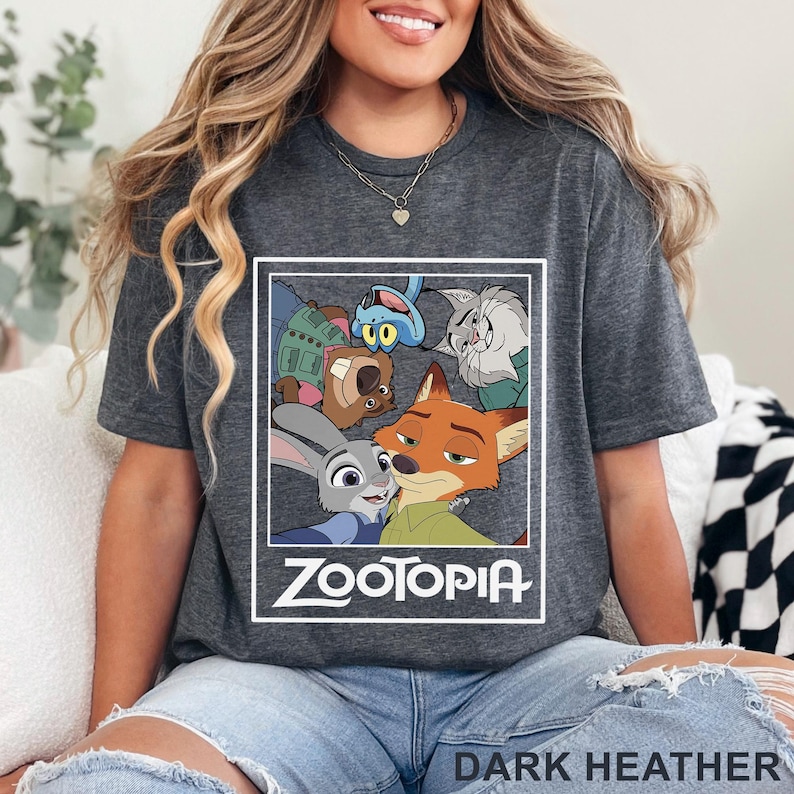 May include: Dark heather grey t-shirt with a Zootopia graphic. The design features characters from the animated film, including Judy Hopps and Nick Wilde, with the word "Zootopia" in white. The shirt is made of a soft material.