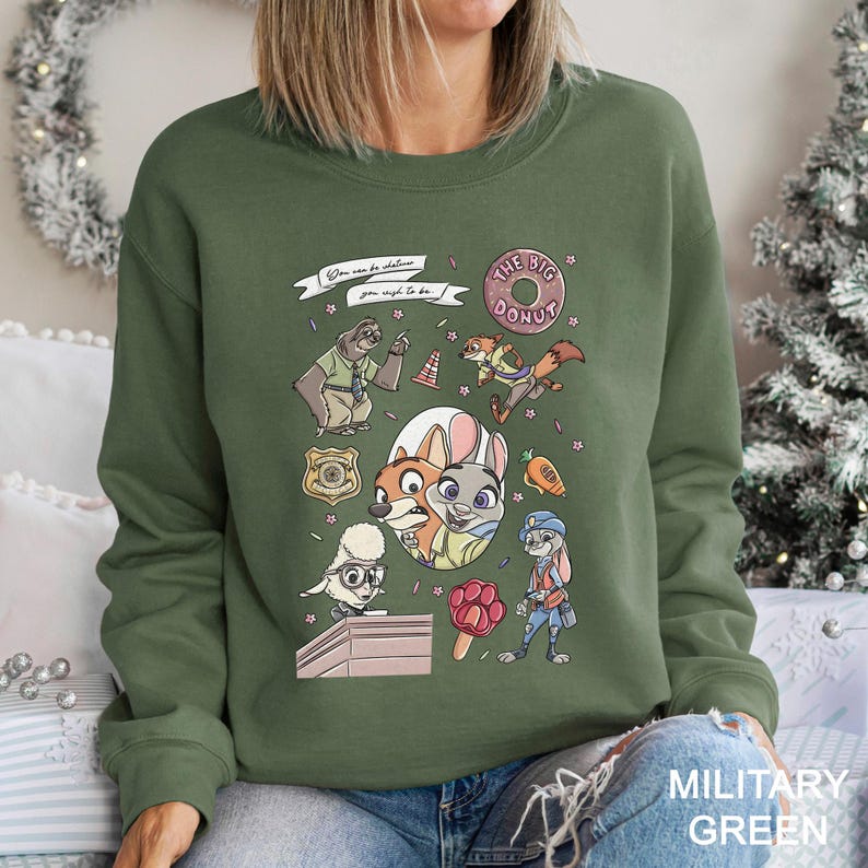 May include: Military green sweatshirt featuring cartoon characters and the text "You can be whatever you wish to be" and "The Big Donut". The design includes a police badge, a sloth, a fox, a bunny, and other characters.