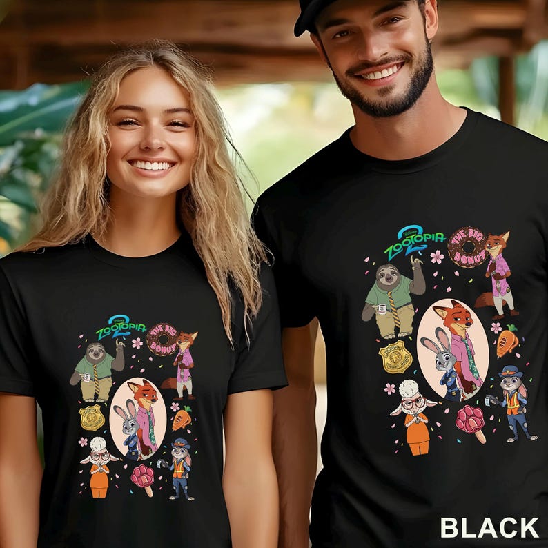 K&ouml;nnte beinhalten: Ein schwarzes T-Shirt mit einem Zootopia 2 Grafikdruck. Das Design zeigt Charaktere wie Nick Wilde, Judy Hopps und Flash sowie einen Donut, eine Karotte, ein Abzeichen und rosa Bl&uuml;tenbl&auml;tter, die um die zentrale ovale Illustration verstreut sind.