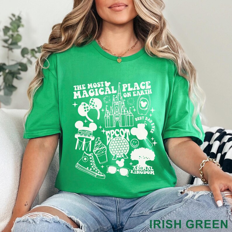 May include: Irish green t-shirt with a white graphic design featuring the text "THE MOST MAGICAL PLACE ON EARTH" and various Disney-themed icons, including a castle, Mickey Mouse ears, and a pair of sunglasses. The shirt is made of a soft material.