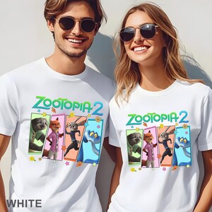 May include: White t-shirts with the text "ZOOTOPIA 2" in green and blue, and character illustrations in colourful rectangular frames. The shirts are worn by two people, and the word "WHITE" is printed at the bottom.
