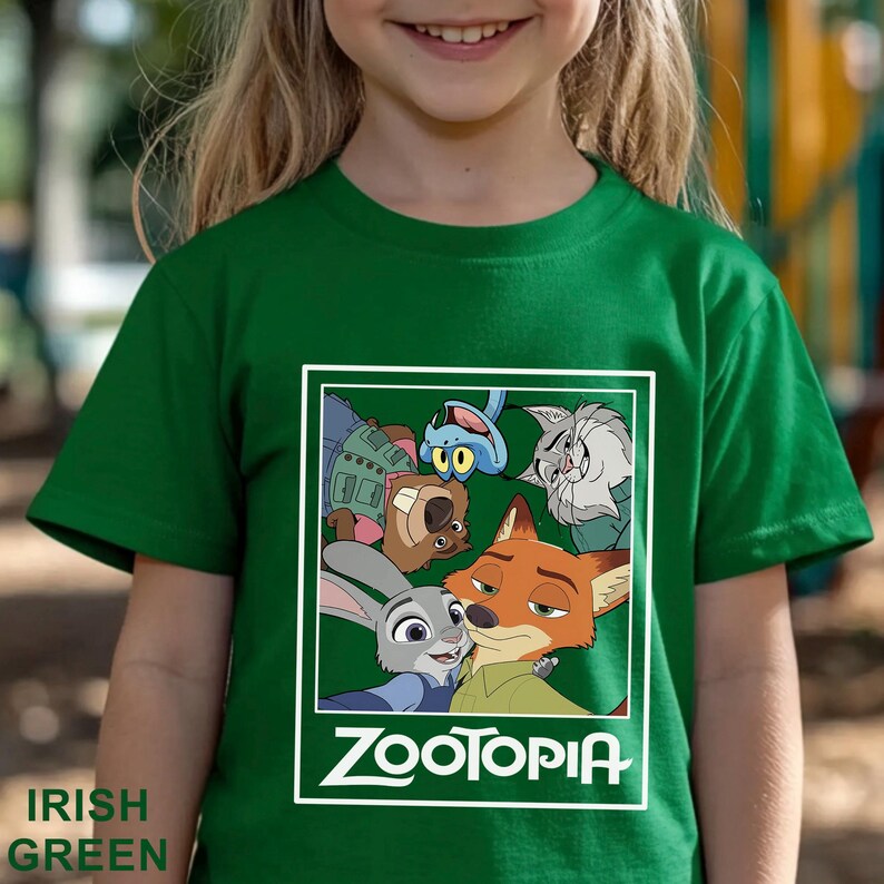 May include: Green t-shirt with a graphic of characters from the animated film Zootropolis. The graphic includes Judy Hopps, Nick Wilde, and other characters. The word "ZOOTOPIA" is printed in white. The words "IRISH GREEN" are printed at the bottom left.