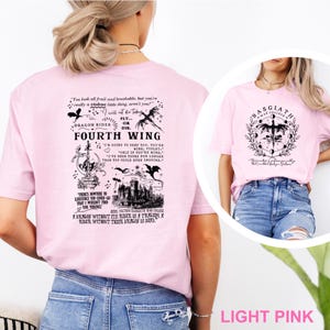 May include: Light pink t-shirts with graphic designs. One shirt features text and illustrations related to "Fourth Wing" and dragons. The other shirt displays a circular design with a dragon and the text "Basgiath War College".
