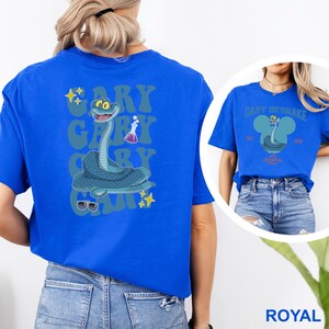 May include: Royal blue t-shirt featuring a cartoon snake design with the text "Gary the Snake". The snake is blue with a smiling face, sunglasses, and a beaker. The design is repeated on the back of the shirt.
