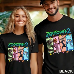 May include: Two people wearing black t-shirts. Each shirt has the text "Zootopia 2" in green and blue, and a graphic of characters from the film. The word "BLACK" is printed at the bottom right of the image.