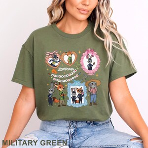 Puede incluir: Una camiseta de color verde oliva con un estampado gr&aacute;fico de los personajes de Zootopia, Judy Hopps y Nick Wilde. El dise&ntilde;o incluye varias ilustraciones enmarcadas, una pancarta con el texto "Welcome to Zootopia" y peque&ntilde;os detalles de estrellas.