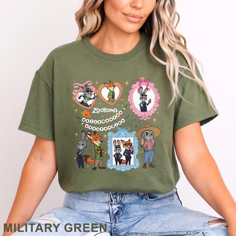 Puede incluir: Una camiseta de color verde oliva con un estampado gr&aacute;fico de los personajes de Zootopia, Judy Hopps y Nick Wilde. El dise&ntilde;o incluye varias ilustraciones enmarcadas, una pancarta con el texto "Welcome to Zootopia" y peque&ntilde;os detalles de estrellas.