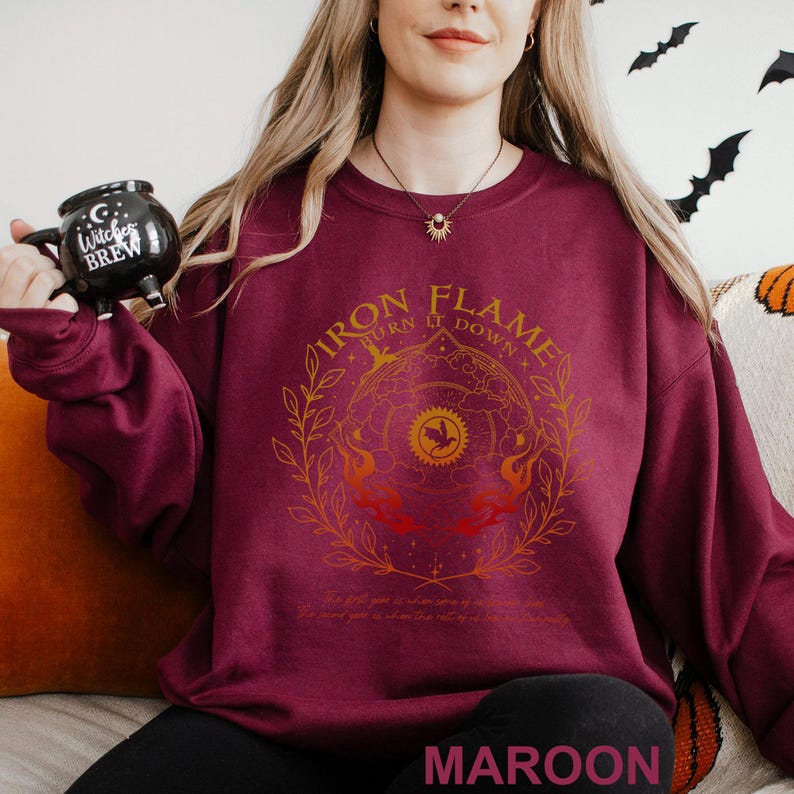May include: Maroon sweatshirt with a gold and orange graphic that reads "Iron Flame Turn it Down". The design includes a circular emblem with a bird and flames. The text "MAROON" is at the bottom.