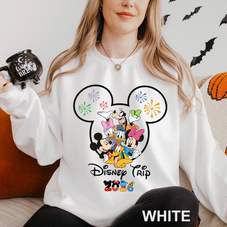 May include: White sweatshirt featuring a Mickey Mouse head design with Disney characters. The design includes Mickey, Minnie, Donald, Daisy, Goofy, and Pluto. The text "Disney Trip 2023" is printed below the characters. The word "WHITE" is printed at the bottom.