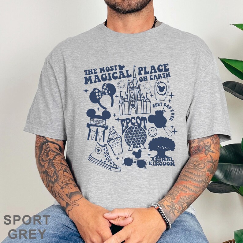May include: Sport grey t-shirt featuring a navy blue graphic design with the text "The Most Magical Place on Earth." The design includes icons of a castle, Mickey Mouse ears, a sneaker, and other theme park elements.