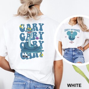 May include: White t-shirt featuring a cartoon snake design with the text "GARY" in blue bubble letters. The snake is blue with a lab flask and sunglasses. A smaller image shows a similar design with the text "GARY DE'SNAKE".