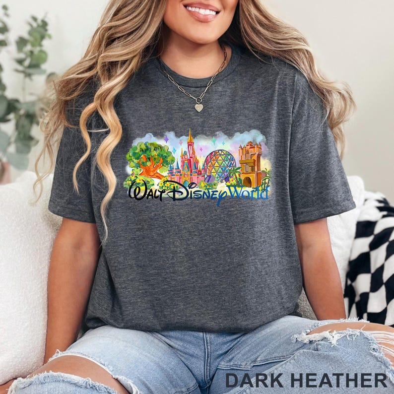 May include: A dark heather gray short-sleeve t-shirt featuring a colorful graphic of the Walt Disney World theme park landmarks, including a tree, a castle, a geodesic sphere, and a tower, with the text Walt Disney World printed in blue.