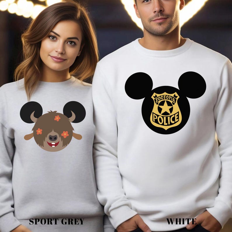 May include: Two sweatshirts, one sport grey and one white, each featuring a cartoon design. The sport grey sweatshirt has a brown character with orange flowers and black ears. The white sweatshirt displays a black Mickey Mouse head with a Zootopia Police badge.