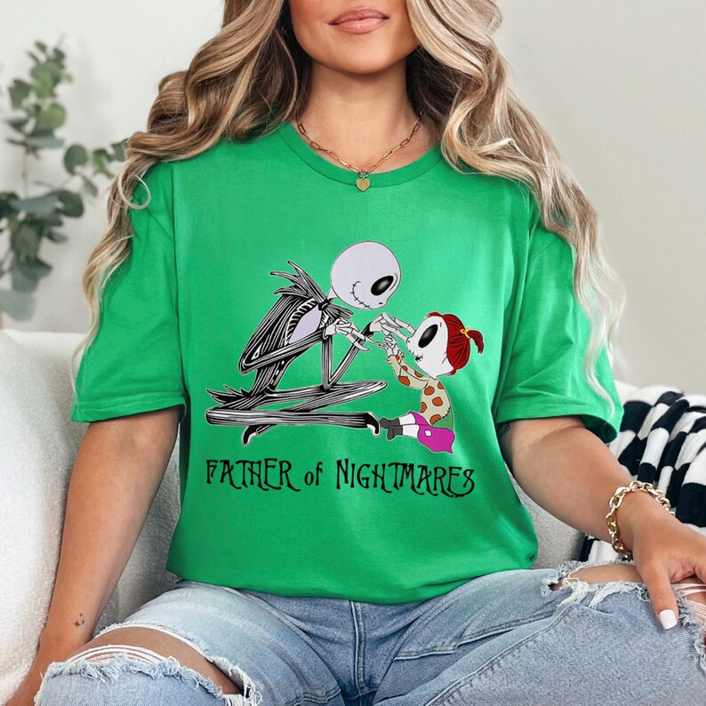 Puede incluir: Camiseta verde con un dise&ntilde;o de Jack Skellington y una figura infantil. El texto "FATHER OF NIGHTMARES" est&aacute; impreso debajo. La camiseta es de material suave. El dise&ntilde;o es de Pesadilla antes de Navidad.