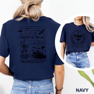 May include: Navy blue t-shirts with graphic designs. One shirt features the text "FOURTH WING" with dragon illustrations and quotes. The other shirt displays a circular design with the text "BASGIATH" and a dragon emblem. Both shirts are casual wear.