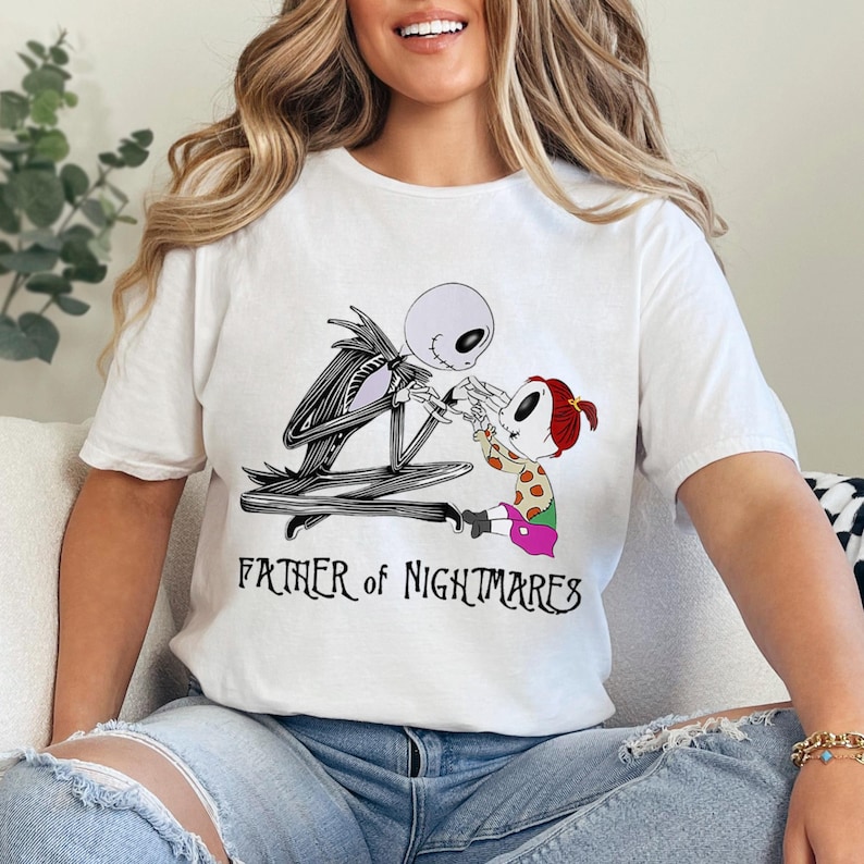 Puede incluir: Camiseta blanca con una ilustraci&oacute;n en blanco y negro de Jack Skellington y Sally. El texto "FATHER OF NIGHTMARES" est&aacute; impreso debajo del gr&aacute;fico. La camiseta es de material suave.