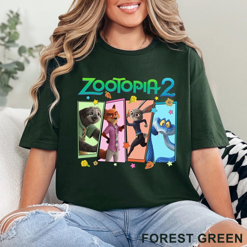 May include: Forest green t-shirt with the text "ZOOTOPIA 2" and a graphic of four characters from the animated film. The graphic includes a sloth, fox, rabbit, and snake. The shirt is a casual style, perfect for everyday wear.