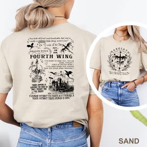 May include: Sand-colored t-shirts with graphic designs. One shirt features the text "FOURTH WING" with dragon and castle illustrations. The other shirt displays "BASGIATH WAR COLLEGE" with a dragon and moon phases. Both shirts have quotes.