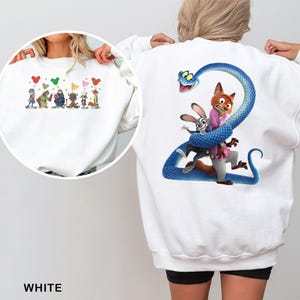 May include: A white long-sleeve sweatshirt featuring a large graphic on the back of a blue snake coiled around a fox and a rabbit. The front chest area displays a smaller graphic of several animated characters holding colorful Mickey-shaped balloons.