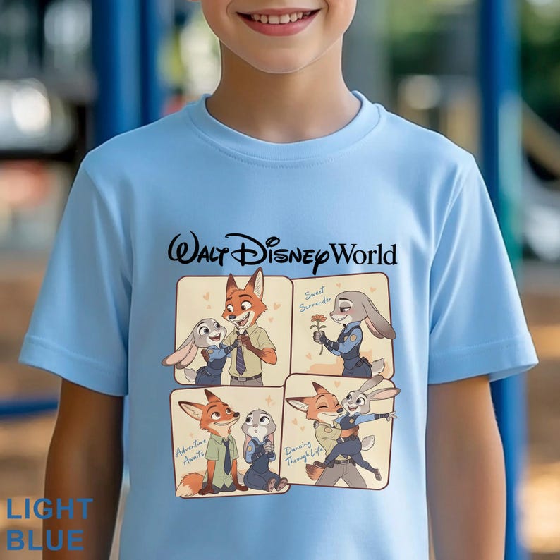 May include: Light blue t-shirt featuring the text "Walt Disney World" in black. The shirt has four panels with cartoon images of Nick Wilde and Judy Hopps from Zootopia. The words "Adventure Awaits", "Sweet Surrender", and "Dancing Through Life" are also visible.