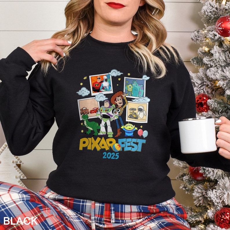Może przedstawiać: Czarna bluza z kolorową grafiką postaci z filmu Pixar i napisem "PIXAR FEST 2025". Projekt zawiera obrazy postaci takich jak Buzz Lightyear i Woody. Bluza ma okrągły dekolt.