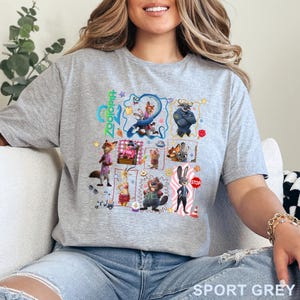 May include: Sport grey t-shirt featuring a colorful graphic of characters from the animated movie "Zootopia". The design includes the movie title and various animal characters in a grid layout. The shirt is made of a soft material.