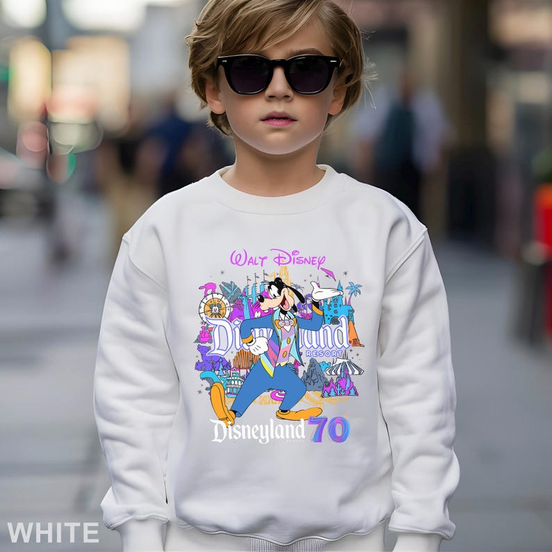 May include: White sweatshirt featuring a colorful graphic of Goofy from Disney's Disneyland Resort. The graphic includes the text "Walt Disney", "Disneyland Resort", and "Disneyland 70". The sweatshirt is a crew neck style.
