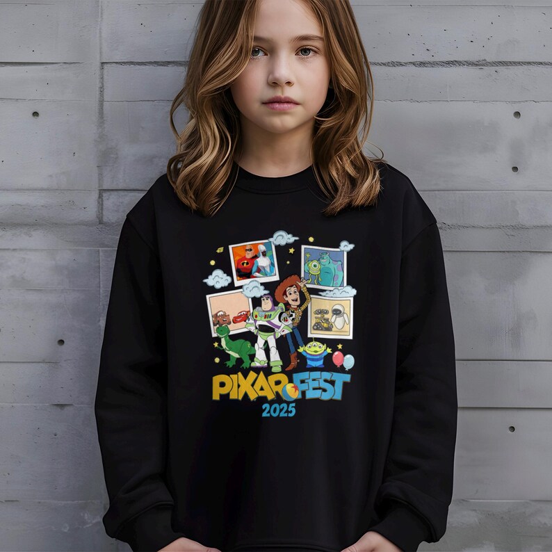 Może przedstawiać: Czarna bluza z kolorową grafiką postaci z film&oacute;w Pixar, w tym Buzz Astral i Woody, z napisem "PIXAR FEST 2025". Projekt zawiera obrazy innych postaci i element&oacute;w z film&oacute;w Pixar.