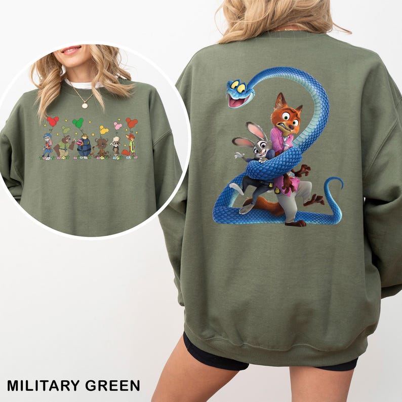 May include: A military green sweatshirt featuring a large graphic on the back of a blue snake coiled around a fox and a rabbit. The front chest area displays a smaller graphic of six cartoon characters holding colorful balloons shaped like mouse ears.